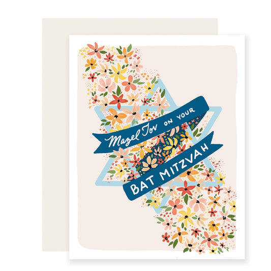 A Bat Mitzvah card in light pink, featuring a light blue Star of David. It's adorned with delicate, beautifully illustrated flowers in shades of orange, pink, yellow, and green. A sweet banner across the card reads "Mazel Tov on your Bat Mitzvah" in a graceful font.