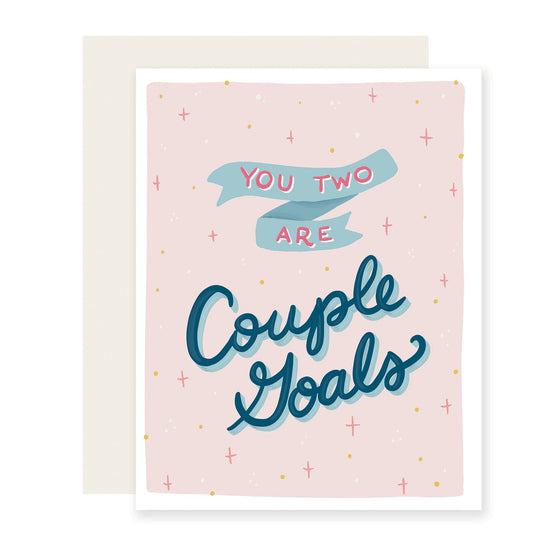 Cute card with a light pink background, featuring a playful blue banner and cursive text saying 'You two are couple goals.' Perfect for that amazing couple who might just make you want to puke from their adorableness!